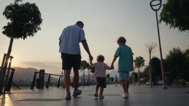Father and Son Holding Hands Walking Together with little brother on the Beach at Sunset