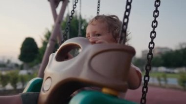 Little boy having fun on chain swing. The simple joys of childhood