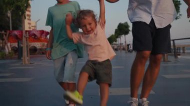 Father and Son Holding Hands Walking Together with little brother on the Beach at Sunset