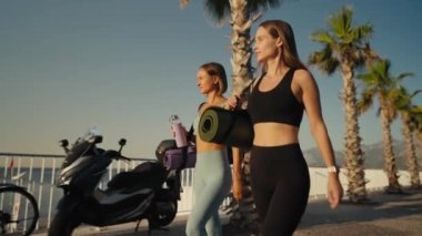 Two beautiful girls jogging at sunset or sunrise on beach. Young caucasian women running together. Brunette and blonde are smiling. Feeling of freedom while running. Concept of cardio.