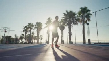 12 year old boy bouncing basketball ball training on ground floor of the court. Basketball player. Workout. Sport activities. High quality 4k footage