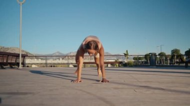 Young woman doing exercise outdoor animal flow innovative movement. Young caucasian woman doing workout at sunrise