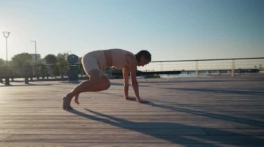 Young woman doing exercise outdoor animal flow innovative movement. Young caucasian woman doing workout at sunrise