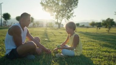 family, leisure and people concept - happy father juggling apples and son learning. Father and son having picnic at summer park. High quality 4k footage