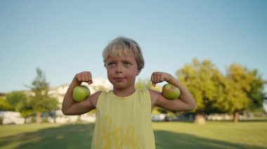 Funny boy with red apples shows biceps. High quality 4k footage