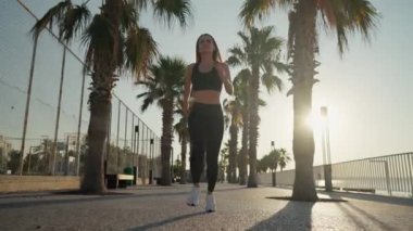 Young active woman jogging along beautiful beach. Running happy woman enjoying their summer morning workout. High quality 4k footage