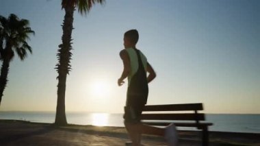 Arka planda güzel bir günbatımı ile koşan bir çocuğun silueti. Genç boksör gün doğumunda antrenman yapıyor.