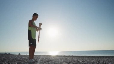 Genç dövüşçü ellerini boks bandajlarıyla sarar, dışarıda kickboks antrenmanı yapar. Gün doğumunda antrenman. Yüksek kalite 4k görüntü