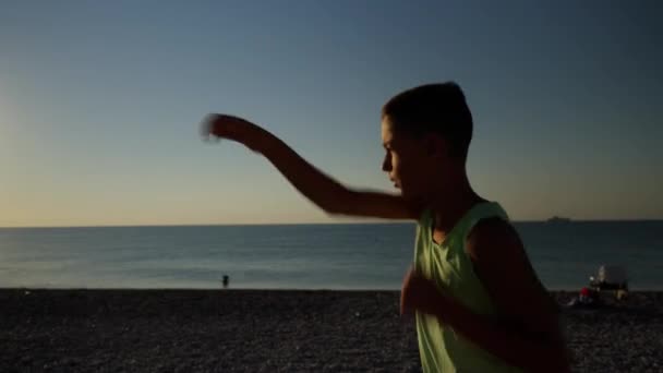 年轻的男性拳击手或空手道选手在日出时在海滩上训练 轮廓拍摄的男孩做影子拳击在早上 高质量的4K镜头 — 图库视频影像