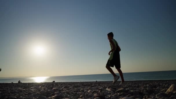 年轻的拳击手早上用石头在海滩上训练 那男孩扔石头 发展壮大 — 图库视频影像