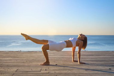 Siluet genç kadın sahilde yoga yapıyor. Kafkasyalı kız doğada yoga yapıyor, sabah deniz kıyısında.