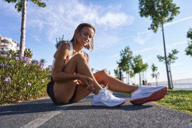 Ayak bileği yaralanması olan koşucu acıyı azaltmak için ayağı tutuyor. Atletizm için açık havada koşma problemi. Yüksek kalite fotoğraf