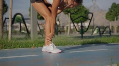 Genç sporcu kadın egzersiz sırasında acı çekiyor veya sakatlanıyor ve koşu pistinde koşuyor.