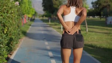 Koşu yapan kadın koşu sırasında sırt ağrısı çekiyor. Arkanı kolla.
