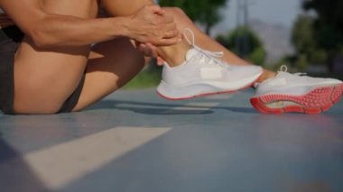 Genç sporcu kadın egzersiz sırasında acı çekiyor veya sakatlanıyor ve koşu pistinde koşuyor.