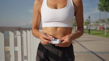 Kablosuz kulaklık takan aktif spor kadını sahilde koşmadan önce kullanıyor.