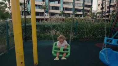 Küçük çocuk arka bahçede salıncakta salıncakta oynuyor. Mutlu Çocuk Swing 'de. Ağır çekim. Yüksek kalite 4k görüntü