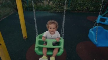 Küçük çocuk arka bahçede salıncakta salıncakta oynuyor. Mutlu Çocuk Swing 'de. Ağır çekim. Yüksek kalite 4k görüntü
