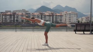 Genç kadın denge egzersizi yapıyor ve spor yogası, spor çorapları ve top, güneşli bir günde açık havada. Yüksek kalite 4k görüntü