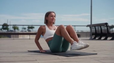 Sportif formda genç bir kadın bisiklet çatırdatma egzersizi yapıyor, tahta zeminde yatıyor, güçlü bir sporcu kadın aktif giysi giyiyor, karın kaslarını çalıştırıyor..