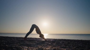 Genç beyaz kadın yoga yapıyor. Genç sağlıklı bir kadın gün doğumunda plajda yoga yapıyor..