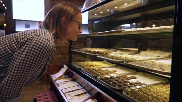 年轻的女人选择蛋糕 冰箱里有各种各样的甜点 顾客看着蛋糕 做出选择 高质量的4K镜头 — 图库视频影像
