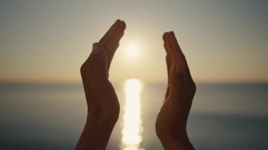 Gün batımında sahilde mutlu bir kız. Parmaklar tarafından yapılmış bir figür. Kalp şeklinde bir kızın elleri. Yaz rüyası. Gün batımında özgürlüğün mutluluğu. Parmakların arasındaki güneş ışığı.