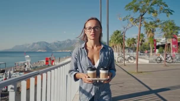 Młoda Biała Kobieta Dwiema Filiżankami Kawy Uśmiechnięta Spacerująca Nad Brzegiem — Wideo stockowe