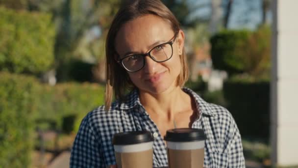若い笑顔の白人女性がテイクアウトコーヒーのカップを持ってきた コーヒーを提供する女性 高品質4K映像 — ストック動画