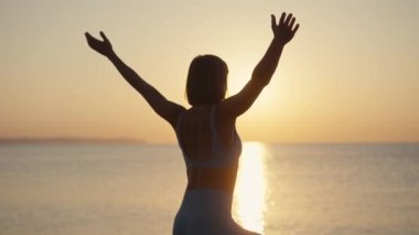 Siluet Kadın, yaz tatili plaj mutluluğu ve rahatlama ile meditasyona yoga pozu veriyor. Yogayla sakin kadın egzersizleri okyanus sahilinde altın günbatımında meditasyon yapar. Ruh Sağlığı