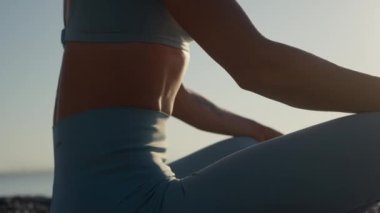 Spor kıyafetli güzel bir genç kadın spor yapıyor, Ateş Logları pozunda oturuyor, karın kasları için nefes egzersizleri yapıyor..