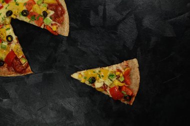 Siyah zemin üzerinde taze pizza ve malzemeler.