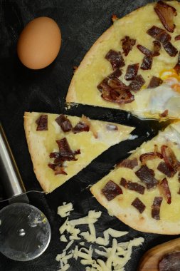 Siyah zemin üzerinde taze pizza ve malzemeler.