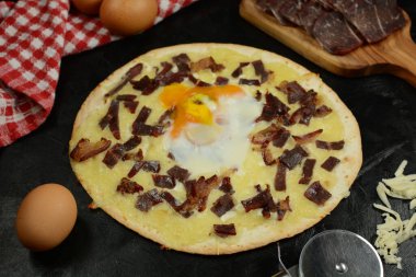 Siyah zemin üzerinde taze pizza ve malzemeler.