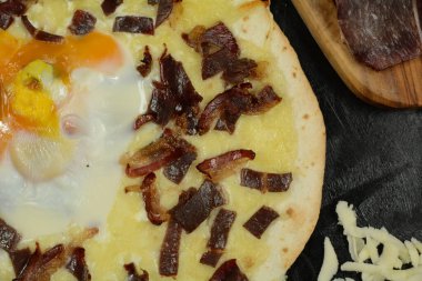 Siyah zemin üzerinde taze pizza ve malzemeler.