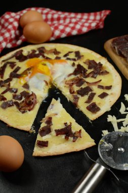 Siyah zemin üzerinde taze pizza ve malzemeler.