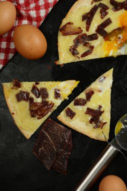 Siyah zemin üzerinde taze pizza ve malzemeler.