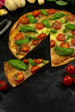 Siyah zemin üzerinde taze pizza ve malzemeler.