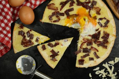 Siyah zemin üzerinde taze pizza ve malzemeler.