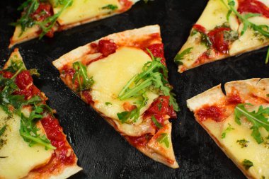 Siyah zemin üzerinde taze pizza ve malzemeler.