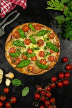 Siyah zemin üzerinde taze pizza ve malzemeler.