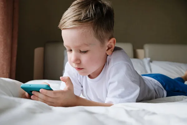 Niño, niño jugando juego móvil, sosteniendo el teléfono inteligente — Foto de Stock