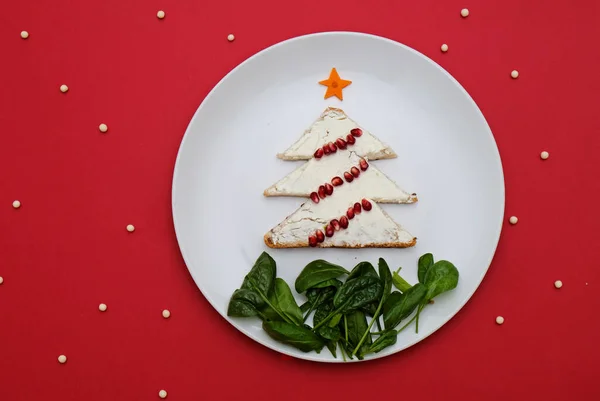 Kreatywne jadalne choinki, sztuka jedzenia. Jedzenie dla dzieci i świąteczny stół. Drzewo wykonane z chleba z serem na talerzu na czerwonym tle. — Zdjęcie stockowe