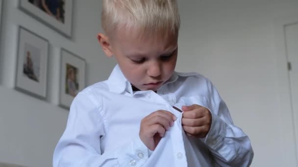 Bonito menino botão acima camisa branca, preparando-se para a escola. Conceito de independência da infância. — Vídeo de Stock
