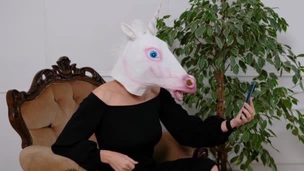 Woman with a head mask of unicorn talking to web camera on smart phone. Social media, Weird funny video — Stock Video