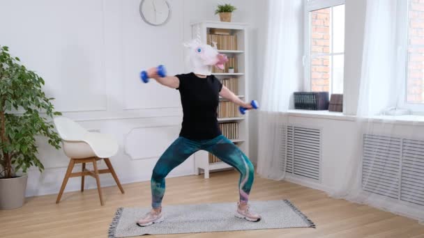 Женщина в голове единорога занимается спортом с гантелями - смешное странное видео — стоковое видео