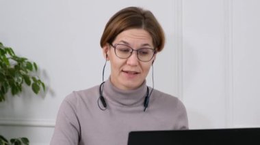 Kadın ofis çalışanı sanal sohbet bilgisayar uygulaması kullanarak müşteriyle konuşuyor. Uzak üniversiteyi ya da laptoptaki öğrenciyi arayan kadın videosu.