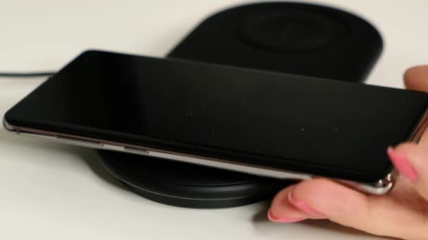 Smartphone noir rechargé sur une borne de recharge sans fil. Concept de technologie sans fil . — Video