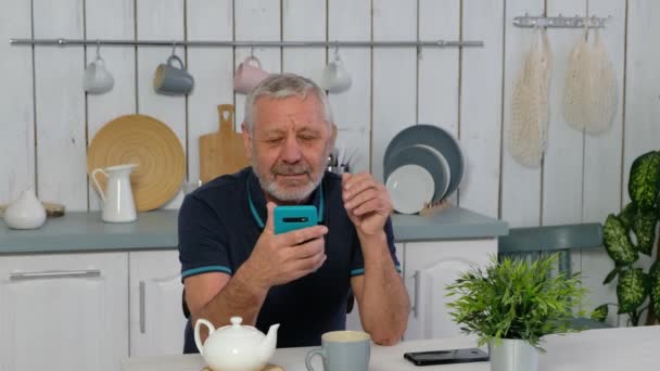 Akıllı telefon tutan, internetten video arayan yaşlı, mutlu yaşlı adam. Büyükbaba modern teknoloji aygıtı kullanarak öğreniyor.. — Stok video