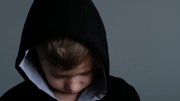 Porträtt lilla barn pojke i huvan tittar på kameran, sorgligt tänkande förolämpat ansikte tittar på kameran, närbild — Stockvideo